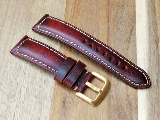 The Berlin burgundy leather watch strap placed on a wood background. 