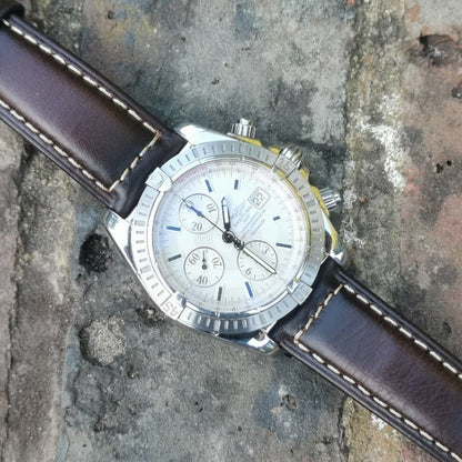 Berlin brown leather watch strap on the Breitling Evolution Chronomat. Placed diagonally on a brick background.